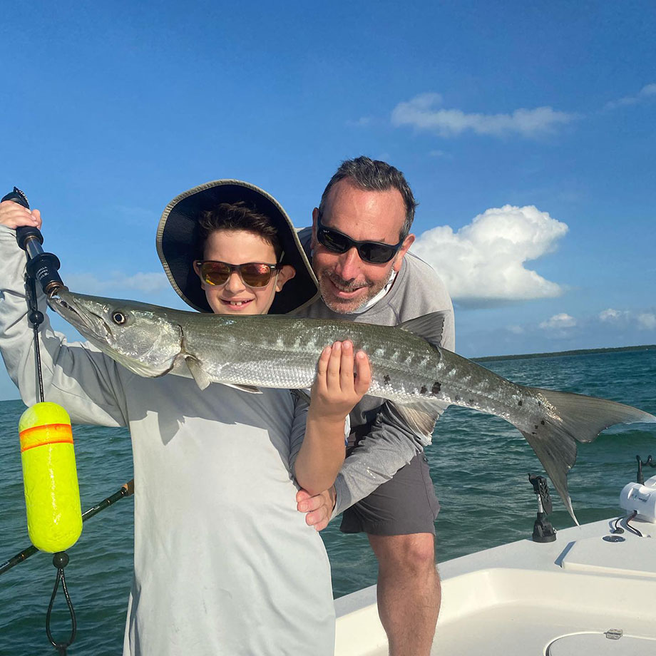 Father and son holding large fish wearing sunglasses with big smiles