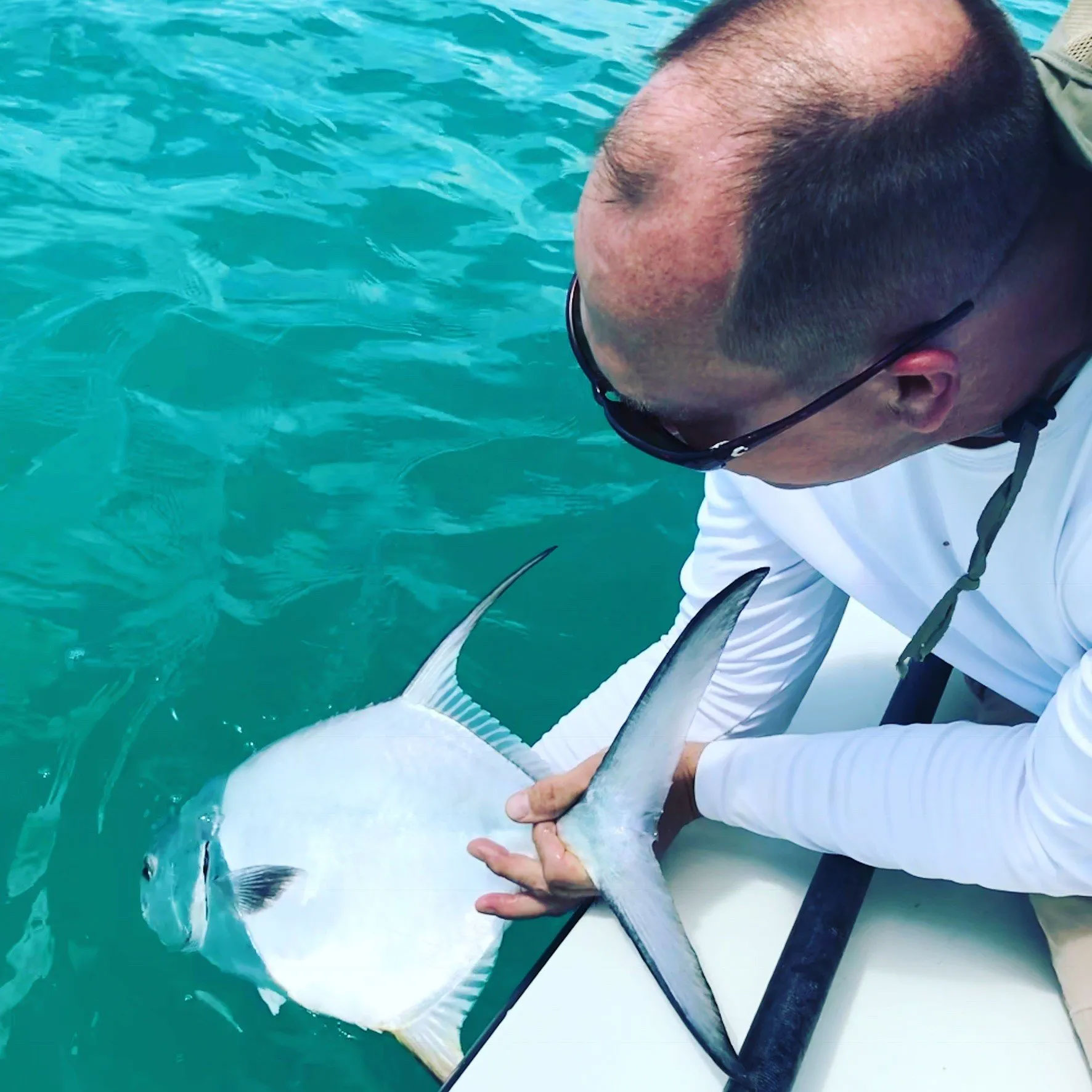 Looking down at man releasing a big fish off the side of a boat