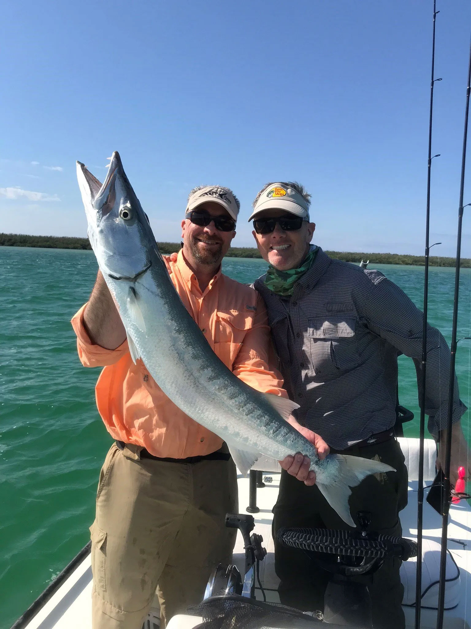 Two men in sunglasses smiling and holding large trout