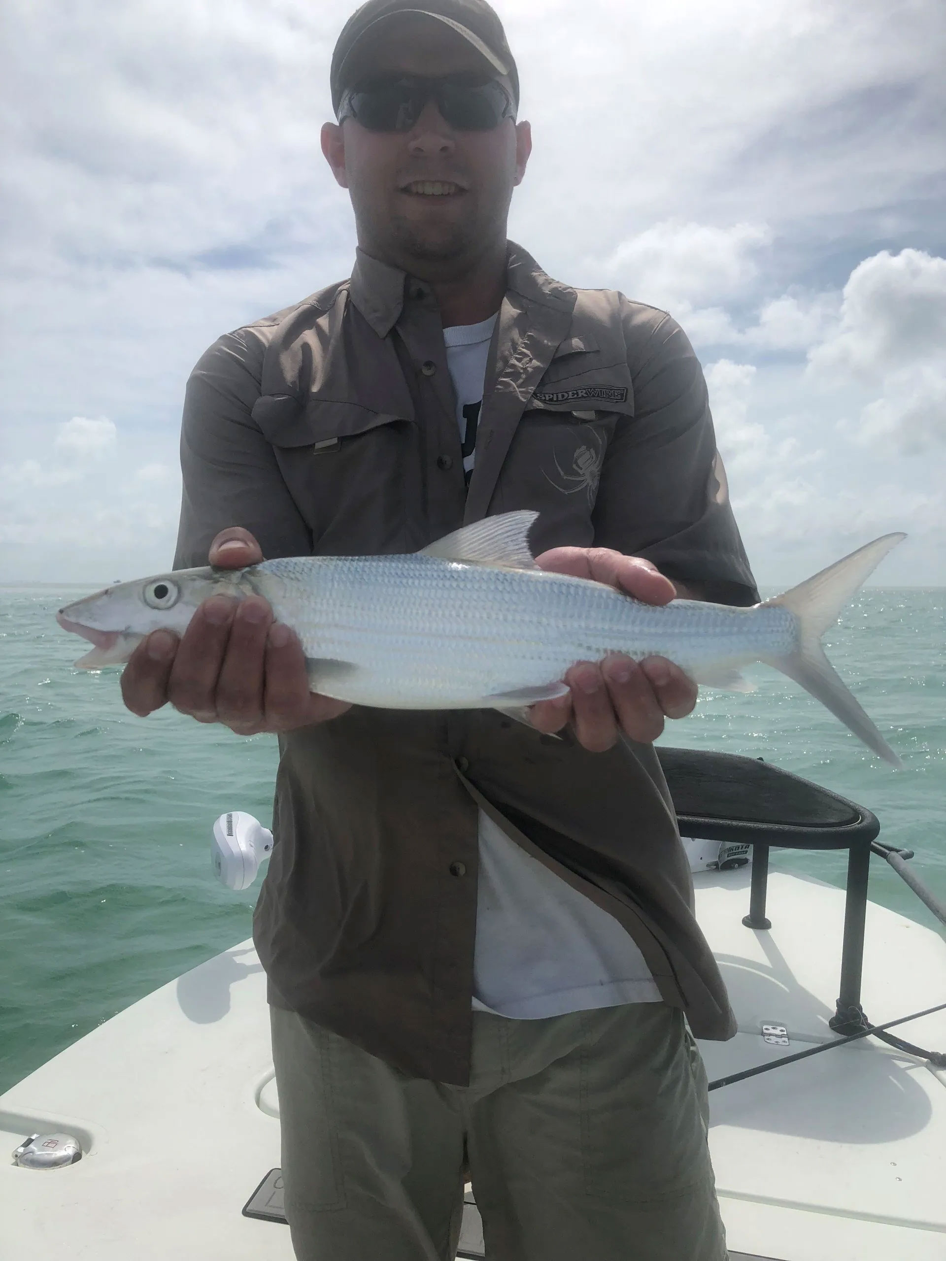 Man in sunglasses holding a fish on fishing boat