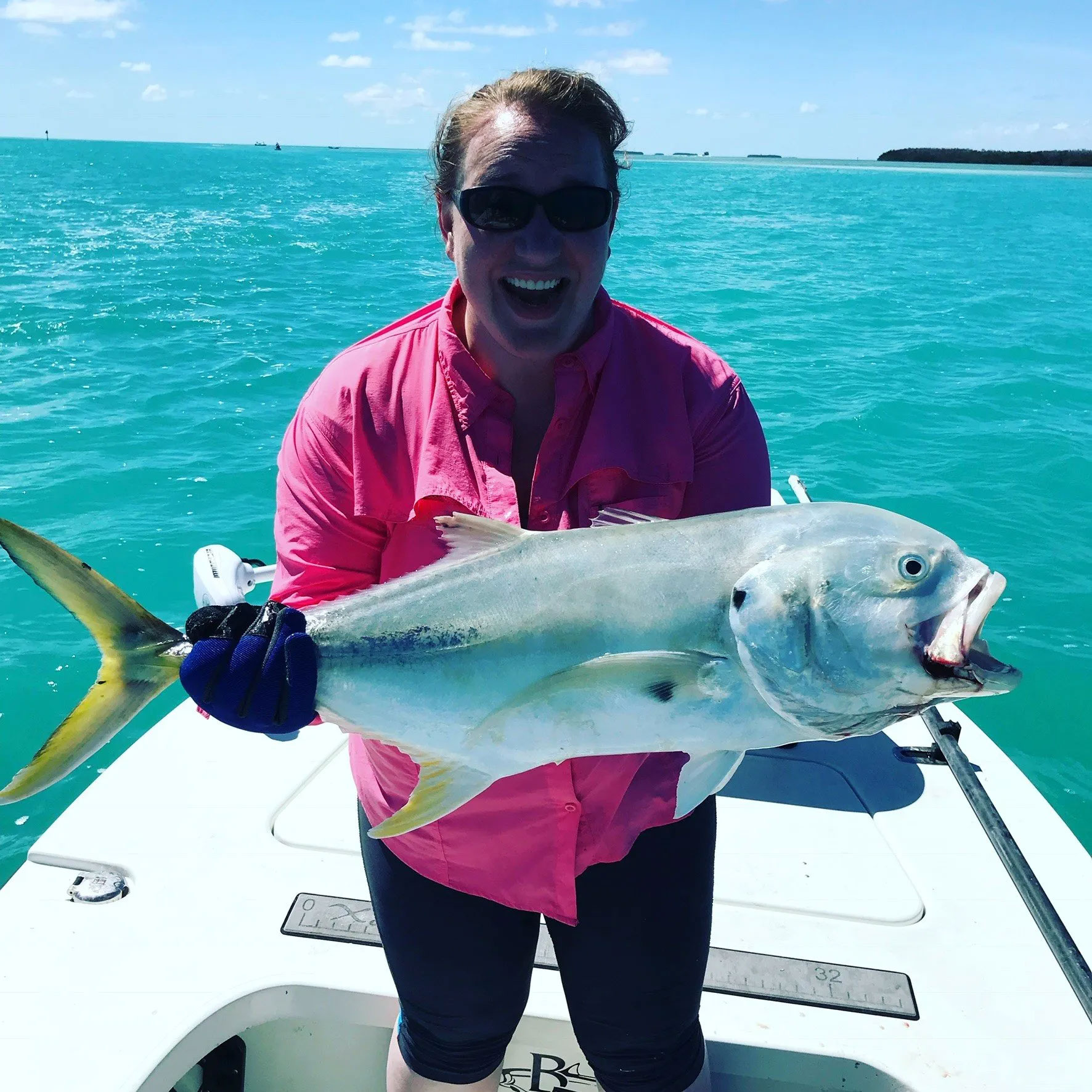 Smiling woman holding big fish on desvk of fishing boat
