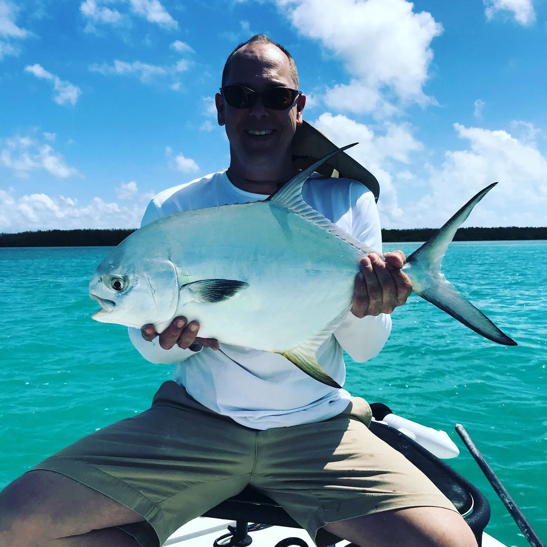 Smiling man in sunglasses holding large fish.