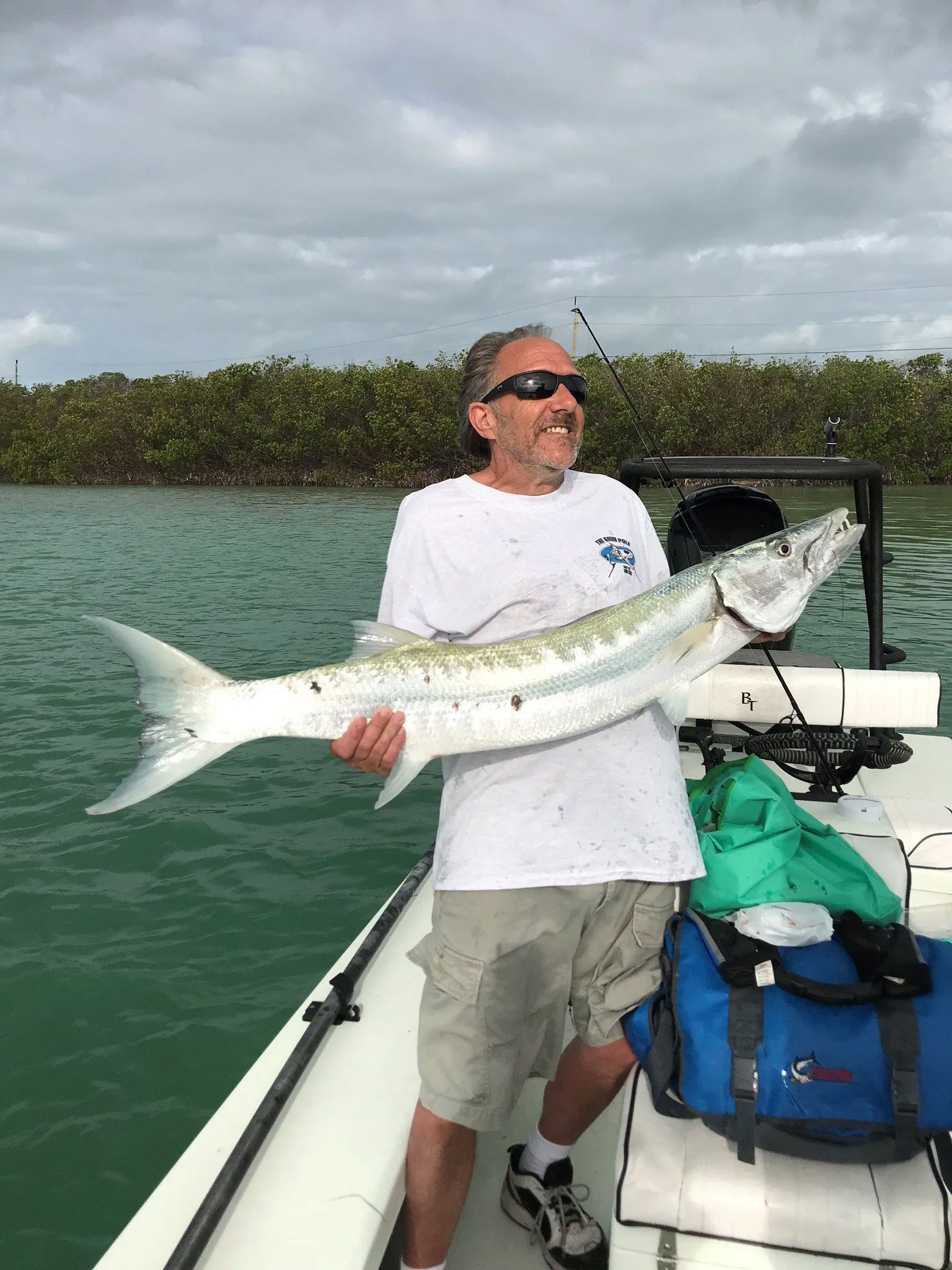 Man wearing sunglasses and a big smile holding a very large fish on a fishing boat