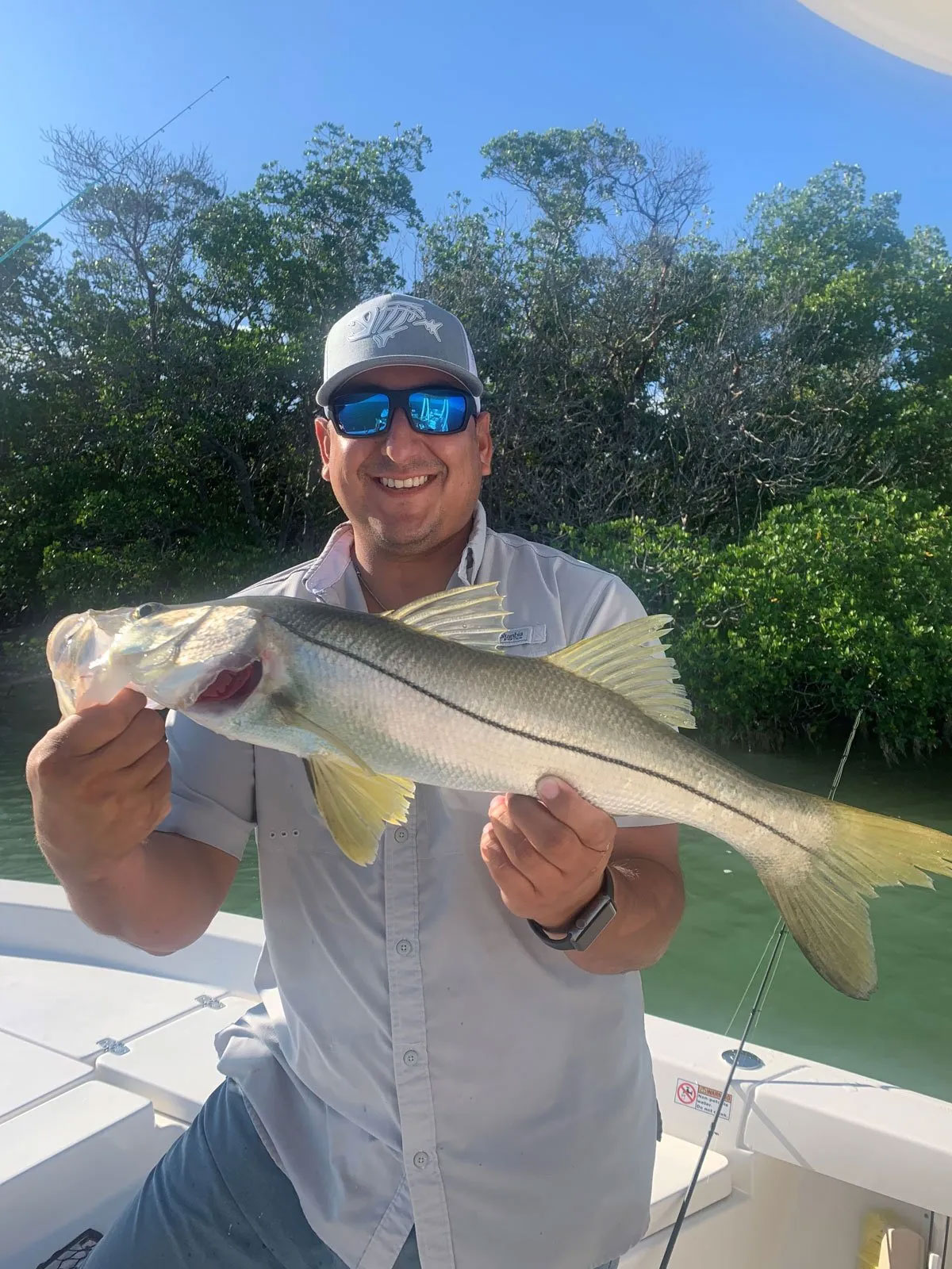 Man wearing baseball cap and sunglasses with big smile holding a large fish