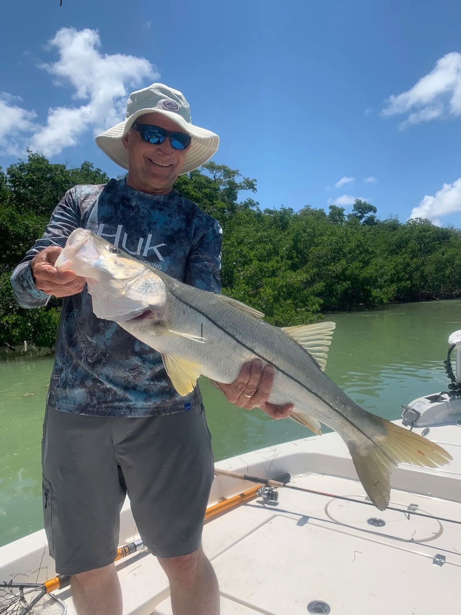 Smiling man in sunglasses and hat holding big fish