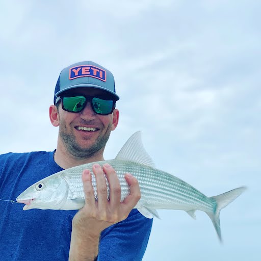Smiling man in sunglasses holding large fish.